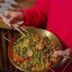 a person holding chop sticks and a wok